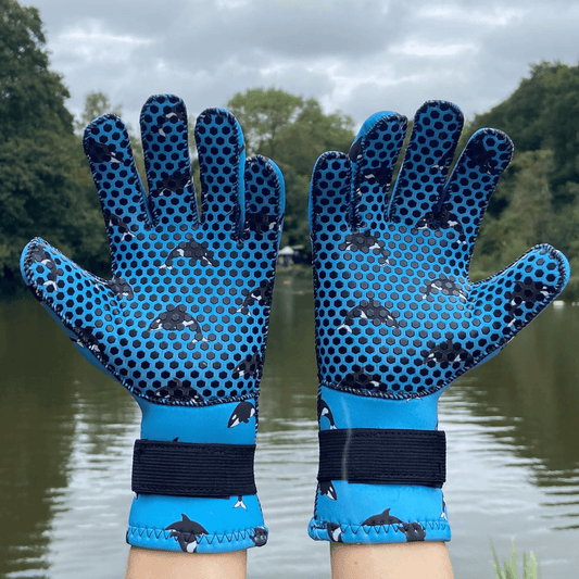 Blue neoprene gloves with black patterns on a background of water and trees
