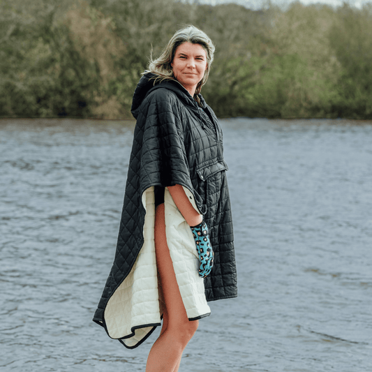Image of woman wearing weatherproof black robe with large front pocket, side popper fastening, hood and white fleece lining