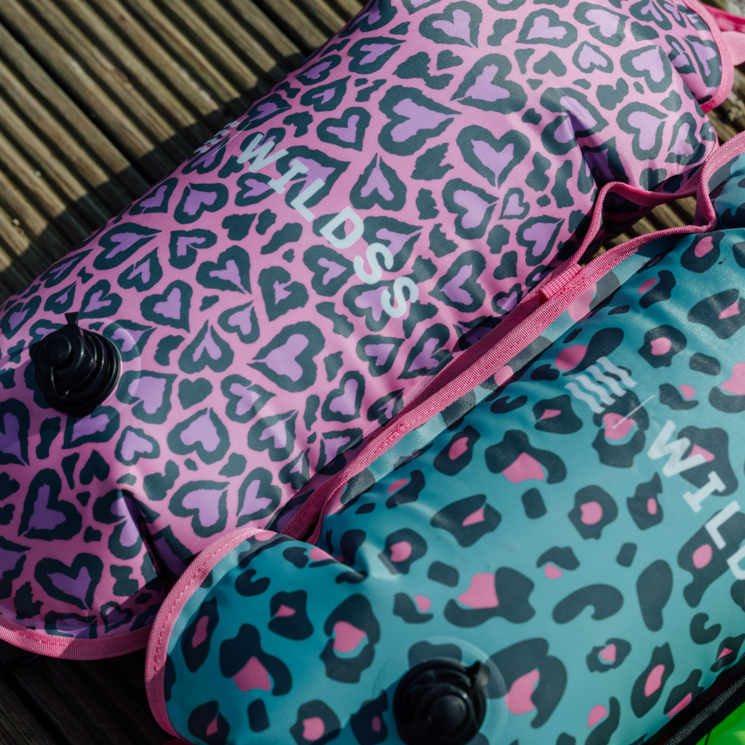 Two inflatable tow floats pink and blue leopard print pattern on a textured surface.