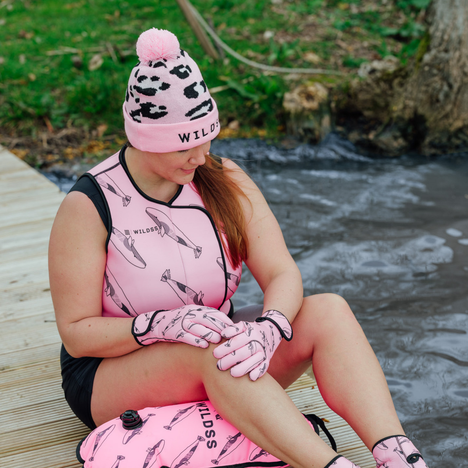 Person wearing a bright pink leopard print beanie hat and matching pink neoprene swimming gear.