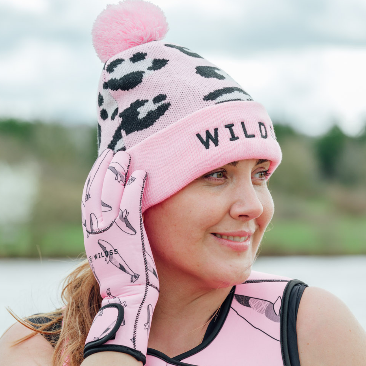 Person wearing a bright pink leopard print beanie hat and matching pink neoprene swimming gear.