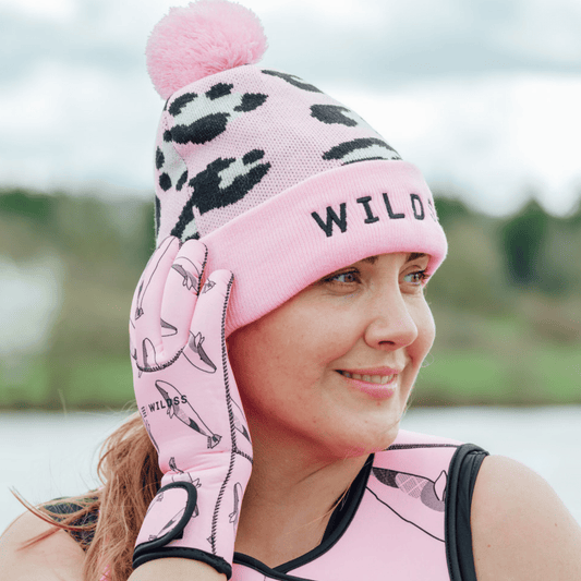 Person wearing a bright pink leopard print beanie hat and matching pink neoprene swimming gear.