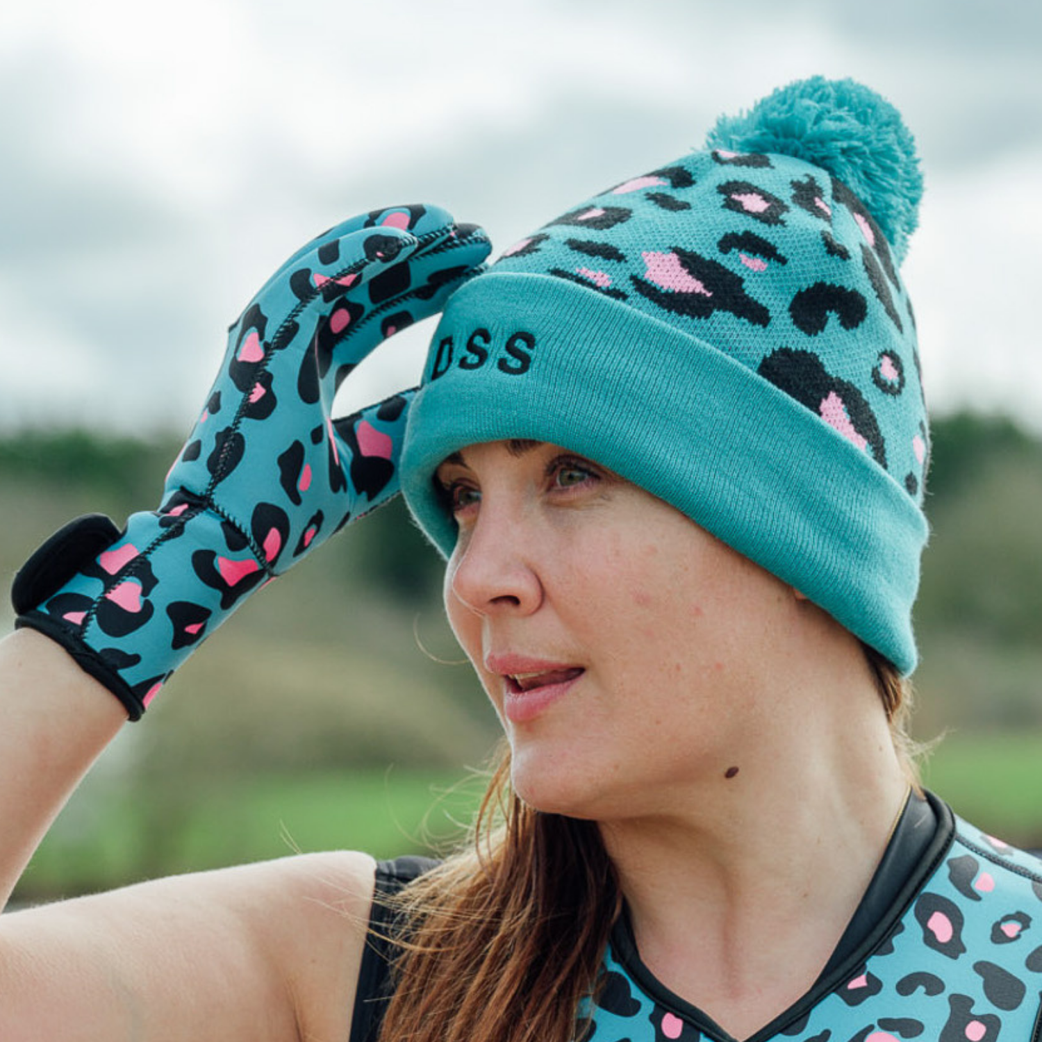 Person wearing a turquoise leopard print beanie and gloves outdoors