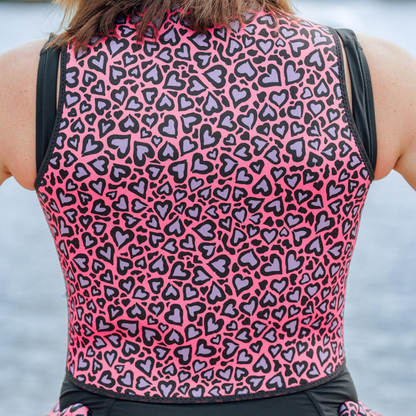 Person wearing a sleeveless neoprene vest with pink and black heart pattern.
