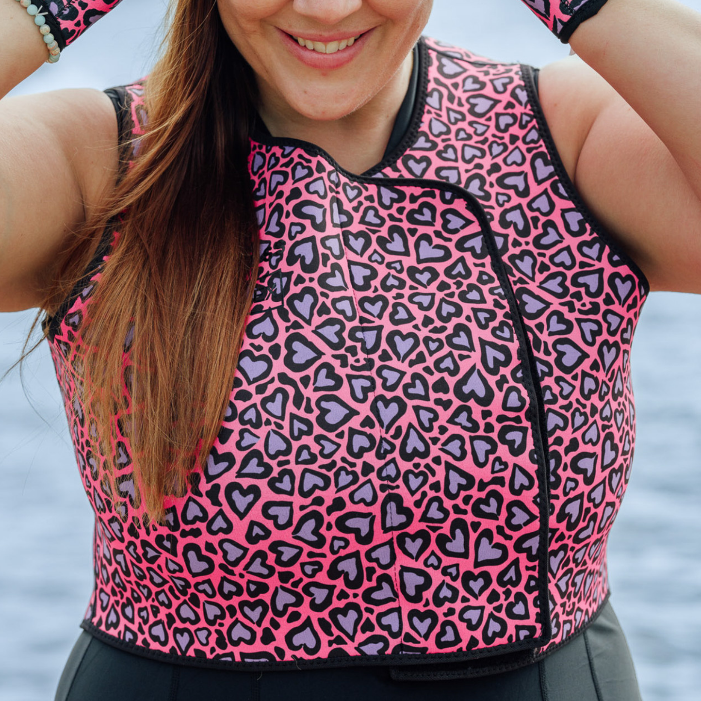 Person wearing a pink and black heart-patterned neoprene vest with a blurred background