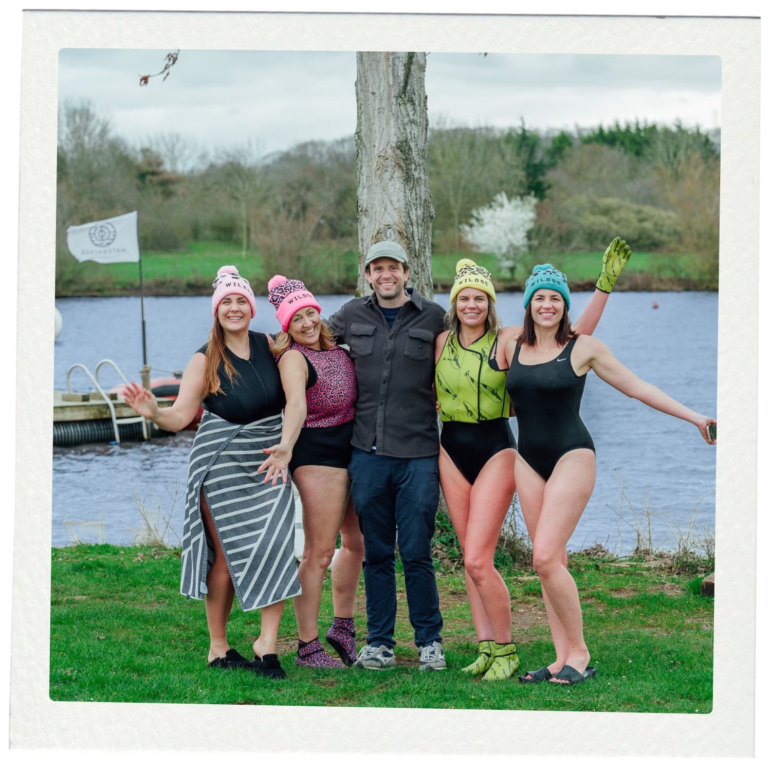 Group of people posing by a lake with colorful hats and gloves