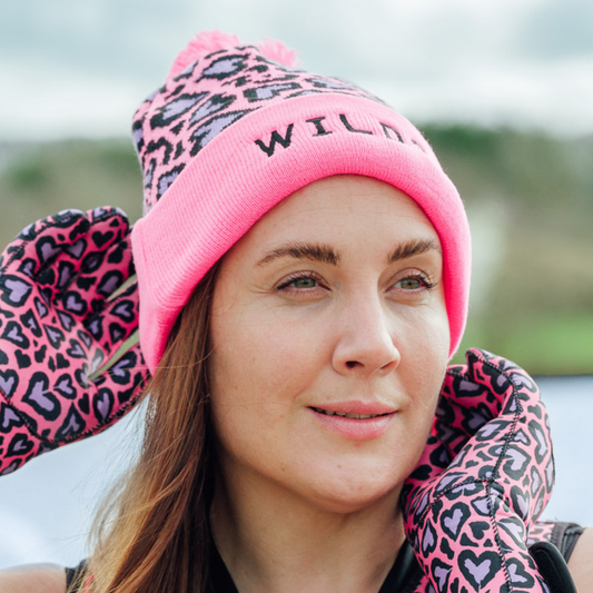 Person wearing a pink leopard print beanie and gloves outdoors