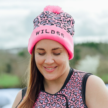 Person wearing a pink and black leopard print beanie with logo on the front