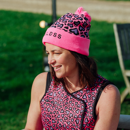 Woman wearing a pink and black patterned beanie and neoprene body warmer outdoors.