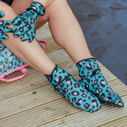 Person wearing blue leopard print neoprene socks sitting by a body of water.