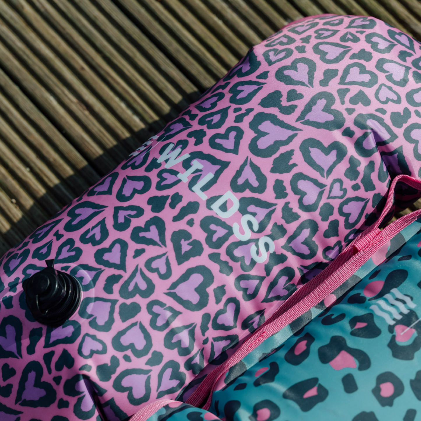 Pink and purple leopard print inflated tow float lay of a wooden dock