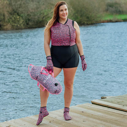 Woman stood by a lake on a dock wearing a black swimsuit and pink leopard print neoprene swimming gear