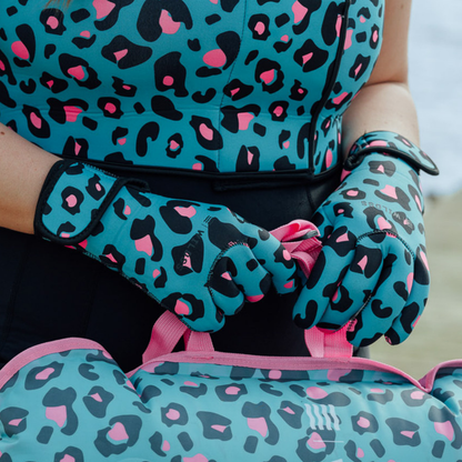 Person wearing turquoise neoprene gloves with black and pink leopard print and a matching neoprene body warmer and tow float