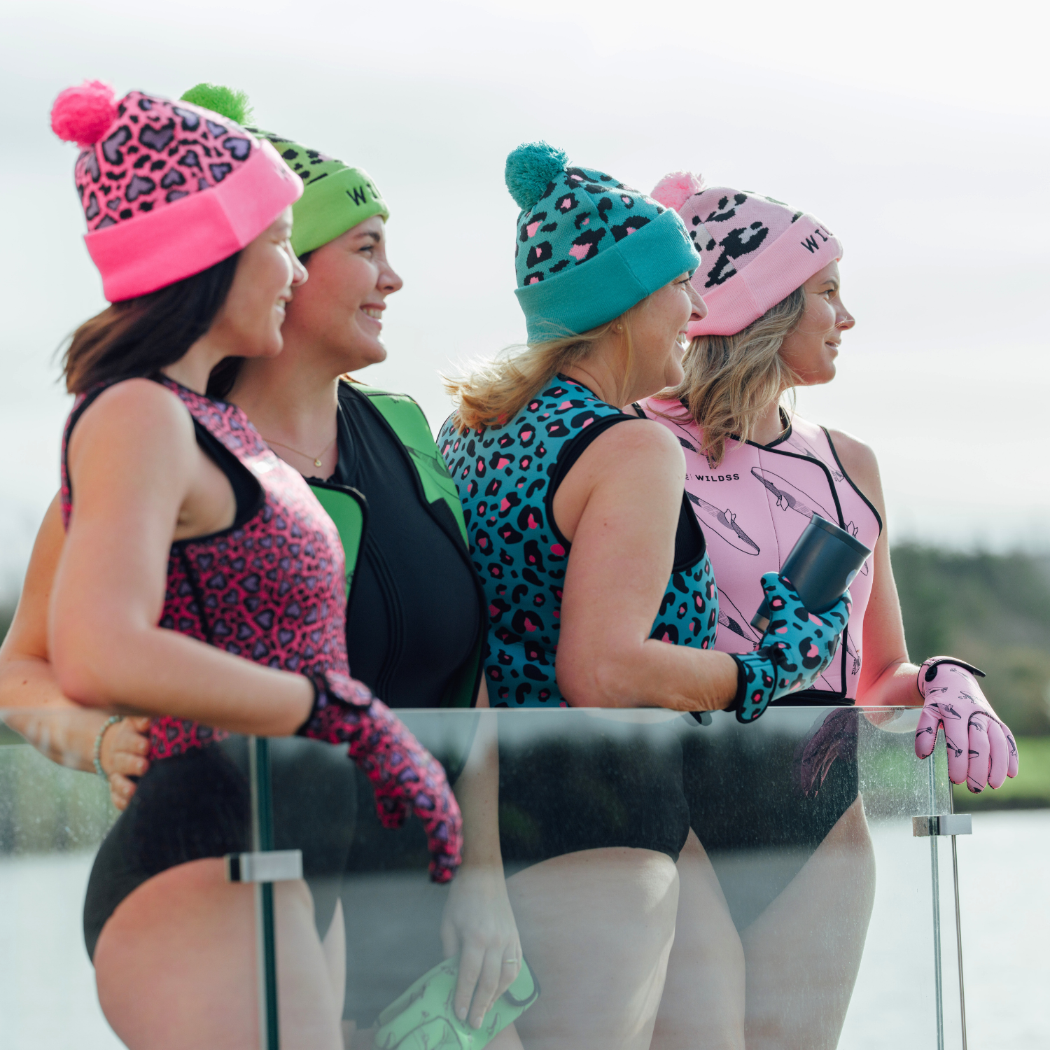 Four women on a boat wearing colorful winter hats and gloves.