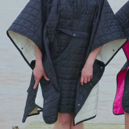 Video of woman wearing weatherproof black robe with large front pocket, side popper fastening, hood and fleece lining