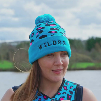 Woman wearing turquoise leopard print woolly beanie hat by a lake