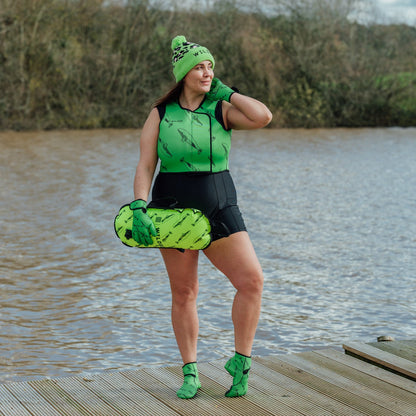 Person wearing green  leopard print hat and neoprene swimming gear by water.